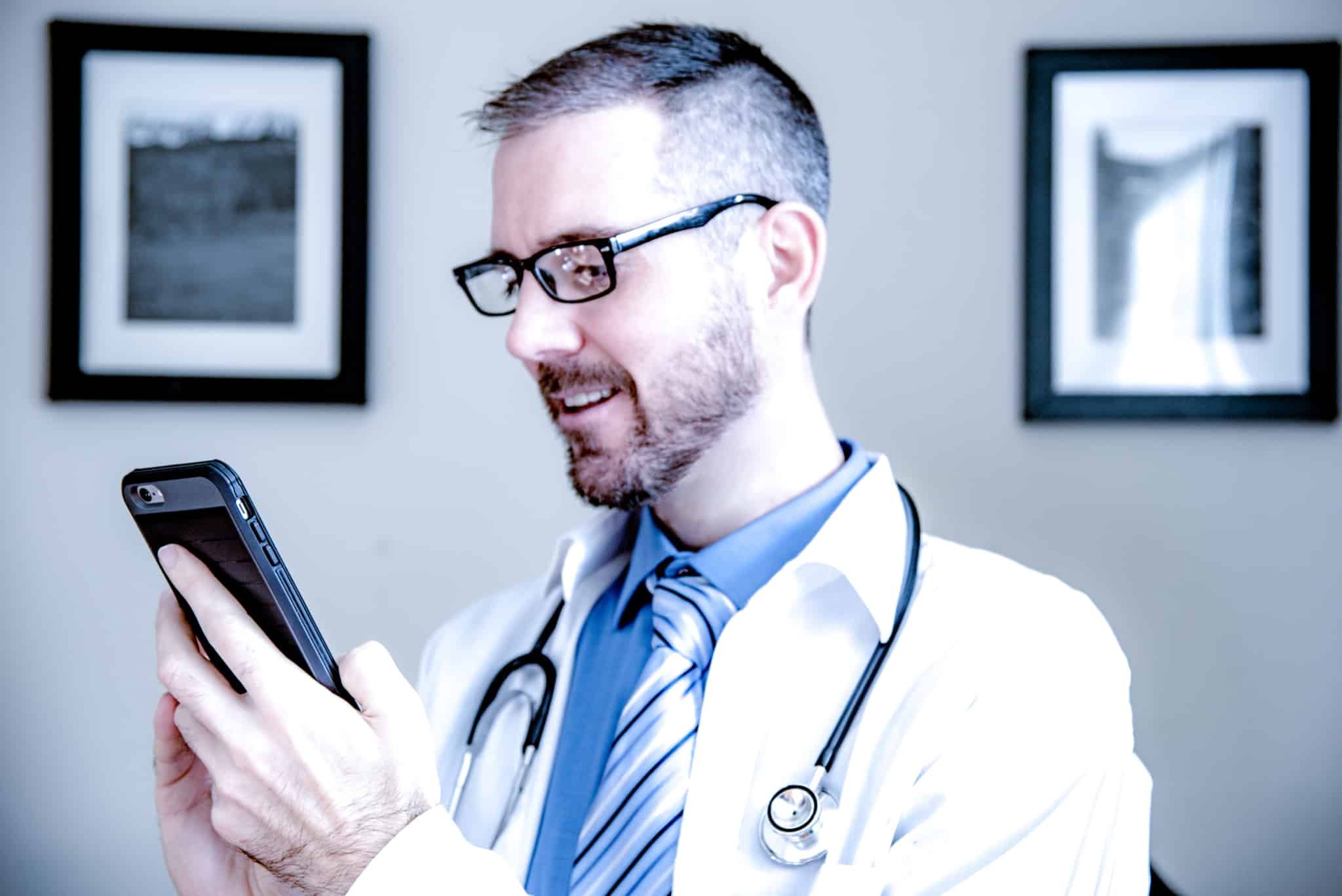 médico de óculos a olhar para o telemóvel